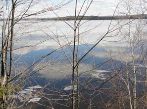 氷が溶け始めた湖に映る青空と雲