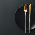ダインアウト イメージ図 Beautiful gold cutlery - fork and knife on black plate on black background. Top View, above. Horizontal. Image from Freepik